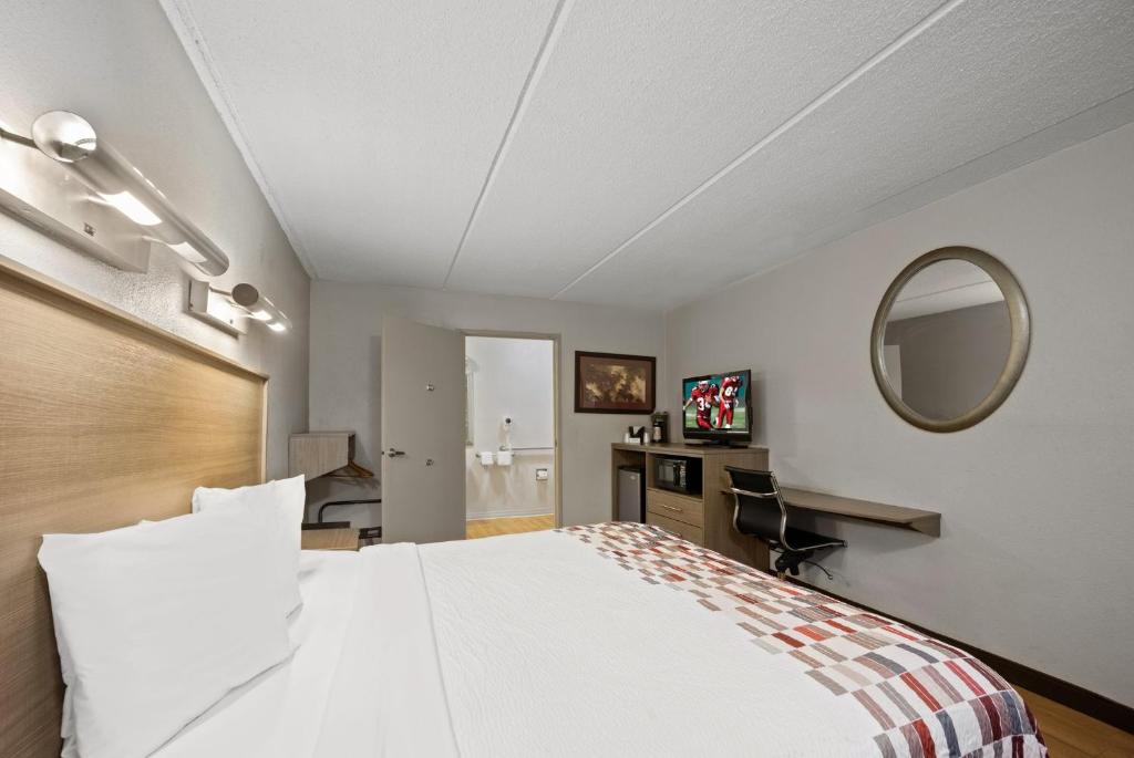 een slaapkamer met een groot wit bed en een spiegel bij Red Roof Inn Greensboro Airport in Greensboro