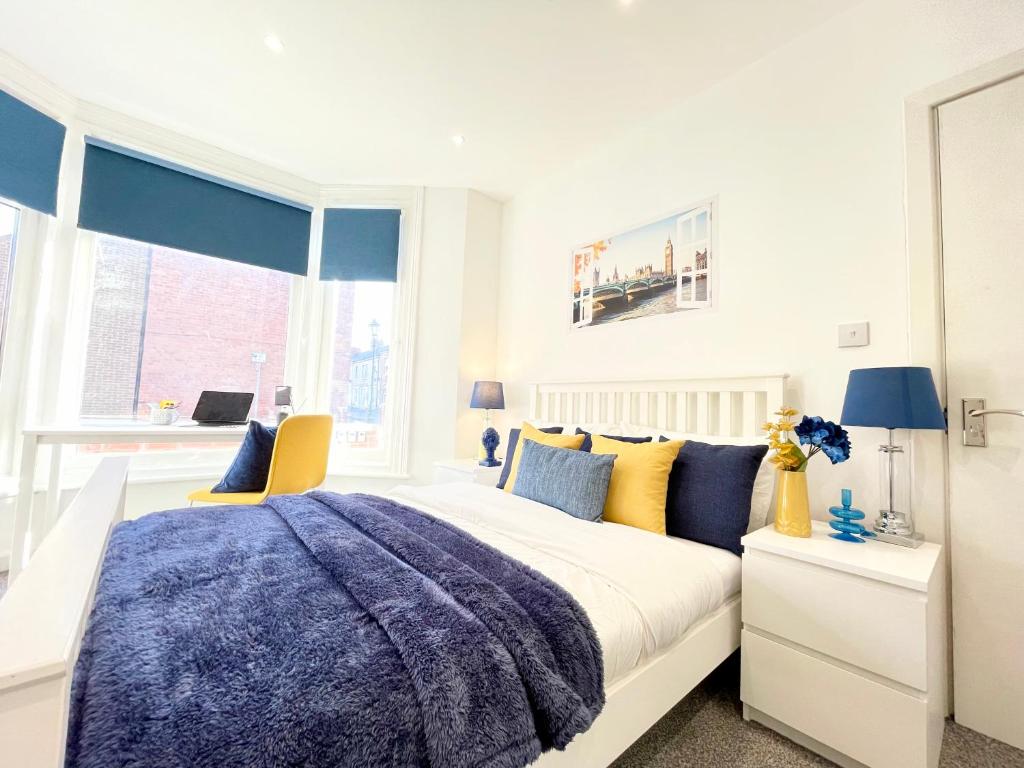 ein Schlafzimmer mit einem großen Bett mit gelben und blauen Kissen in der Unterkunft Sandringham House Serviced Rooms in Hartlepool