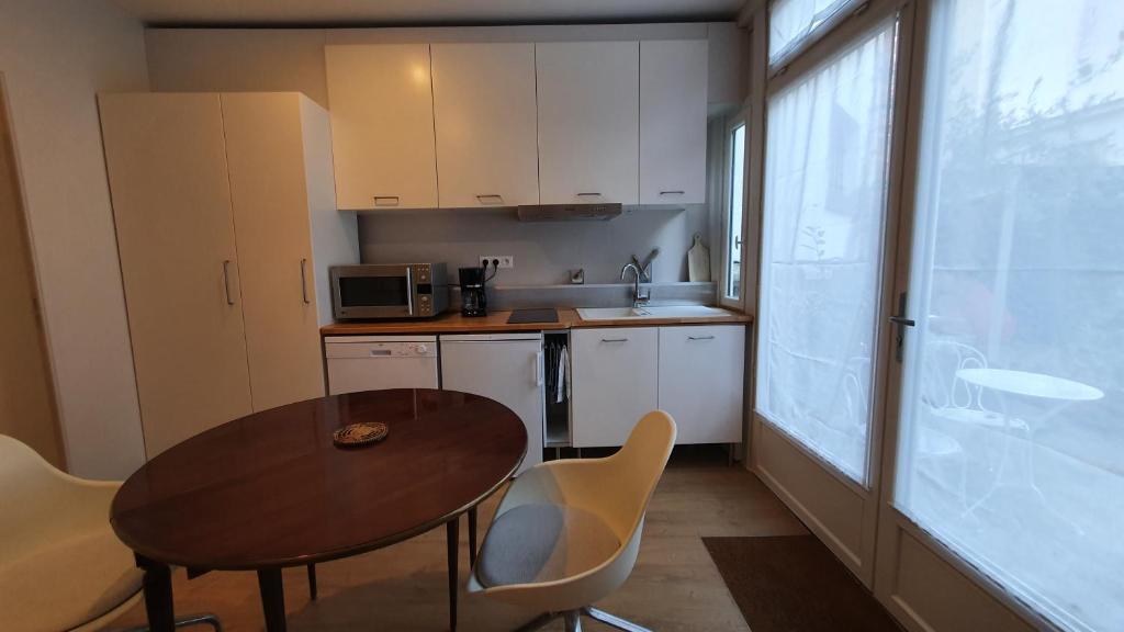 una pequeña cocina con mesa de madera, sillas, mesa y mesa. en Studi'O, en Maisons-Laffitte