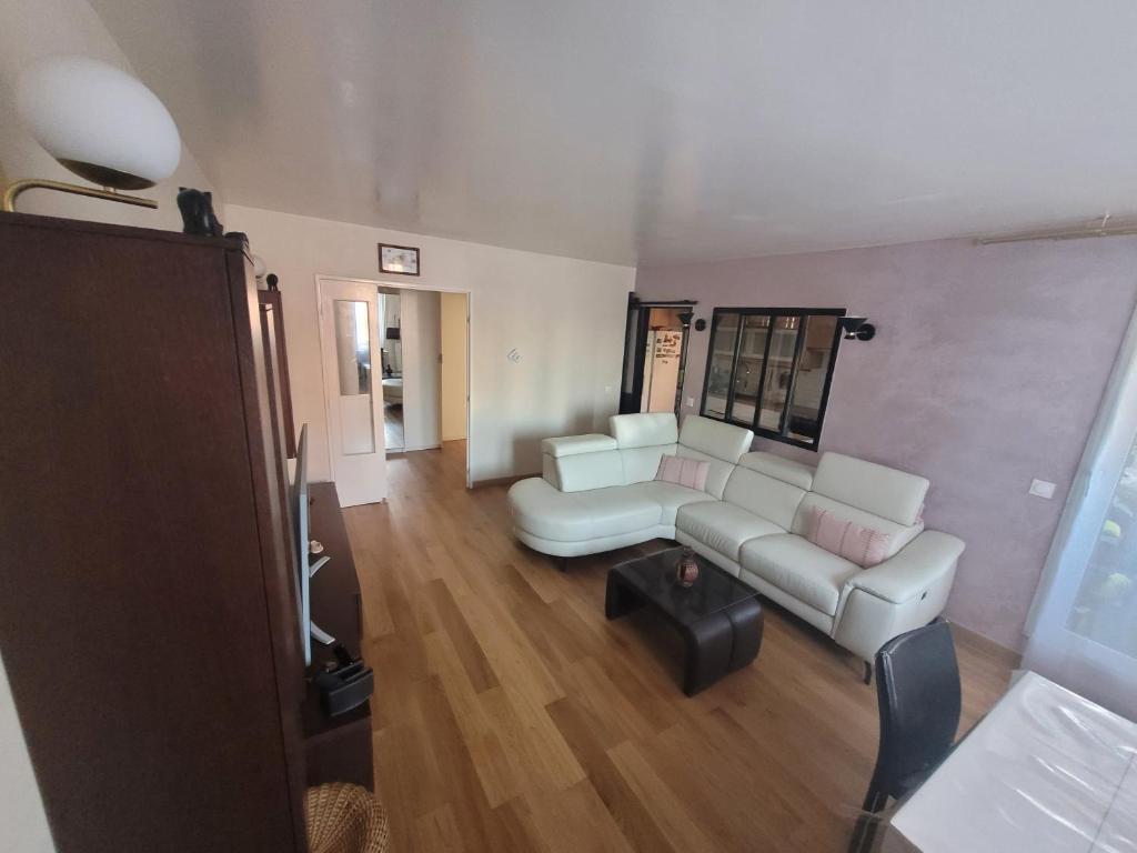 uma sala de estar com um sofá e uma mesa em APPARTEMENT AGREABLE PROCHE DES SITES JO 2024 em Élancourt