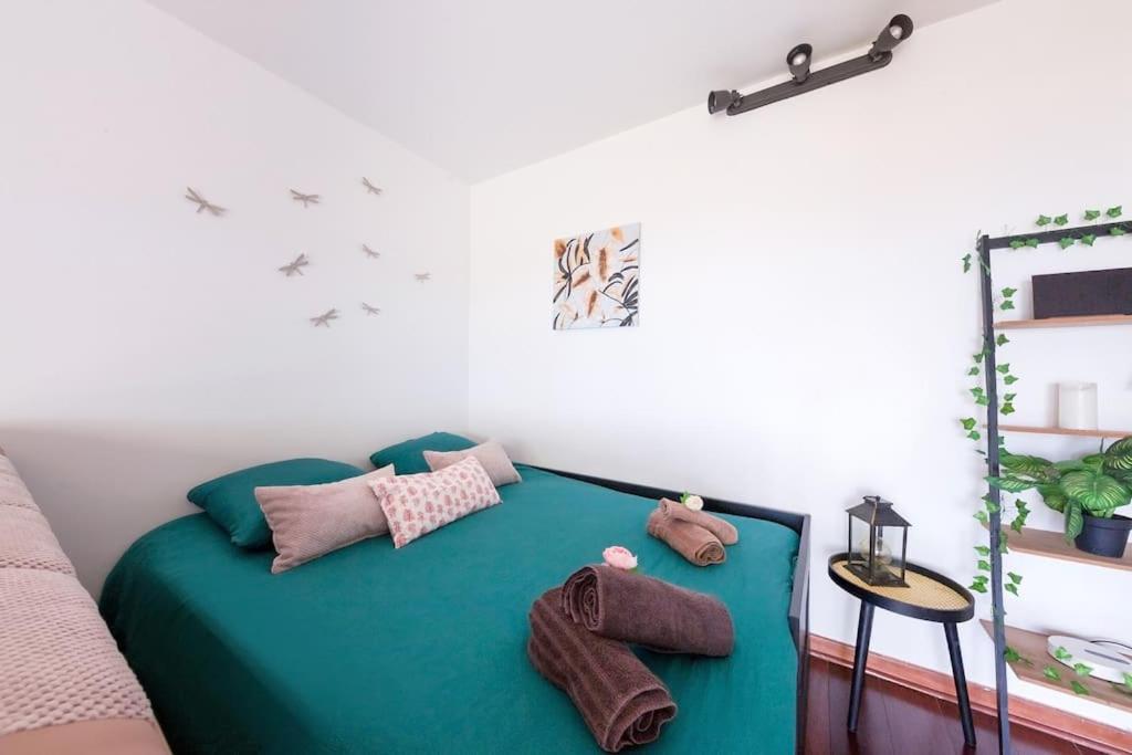 - une chambre avec un lit vert et des oreillers dans l'établissement Le Jardin du Raincy Paris/Disney JO 2024, à Le Raincy