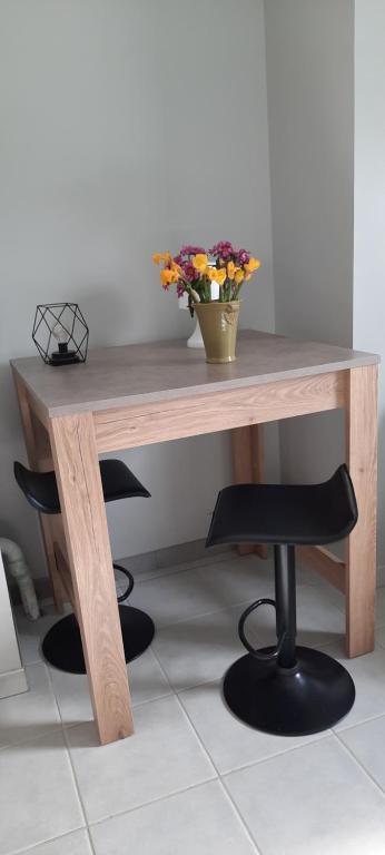a wooden table with a vase of flowers on it at Studio situé centre ville in Parthenay