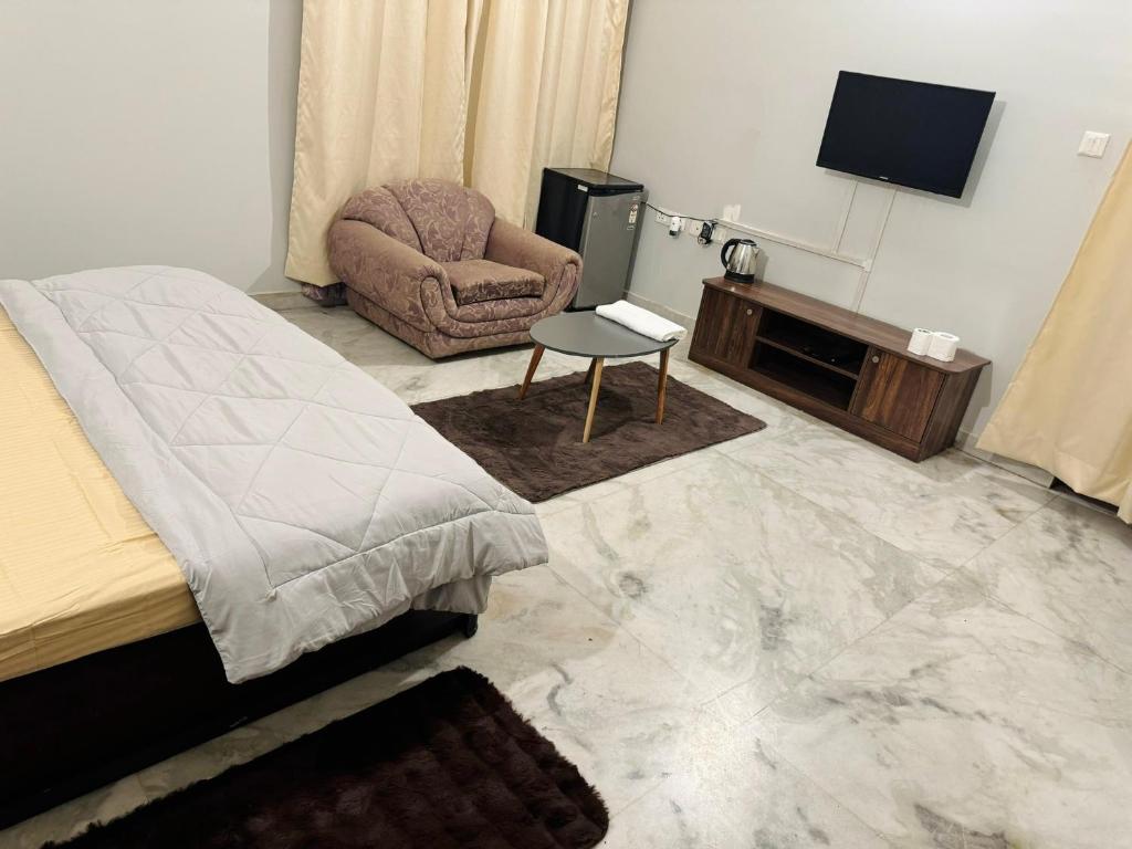 a bedroom with a bed and a chair and a television at Riya Villa - Entire Villa (Kaashi Flora) in Varanasi