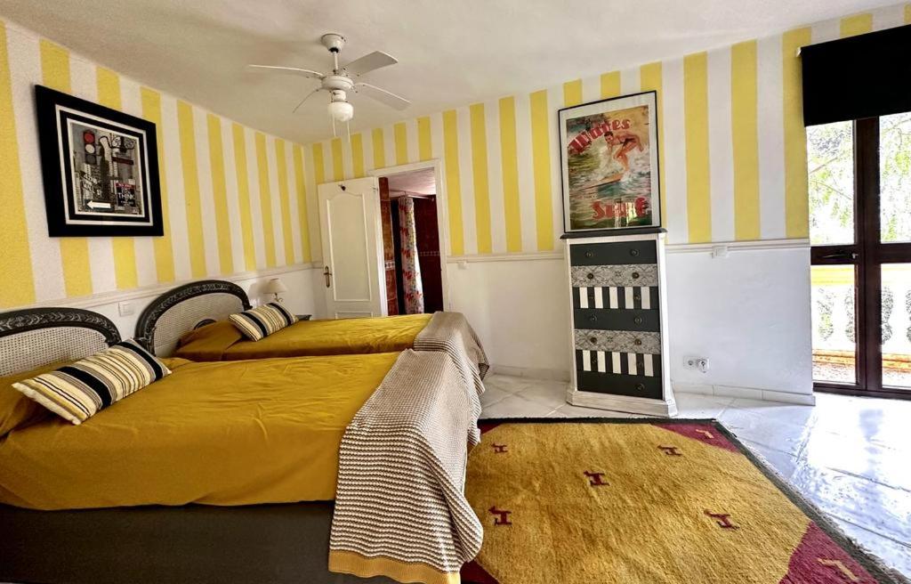 2 Betten in einem Zimmer mit gelben und weißen Streifen in der Unterkunft Villa in Marbella center in Marbella