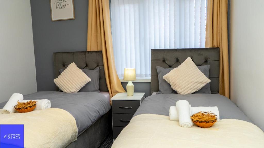 dos camas sentadas una al lado de la otra en un dormitorio en 2ndHomeStays-Dudley-Suitable for Contractors and Families, Parking available for 3 Vans, Sleeps 12 en Dudley