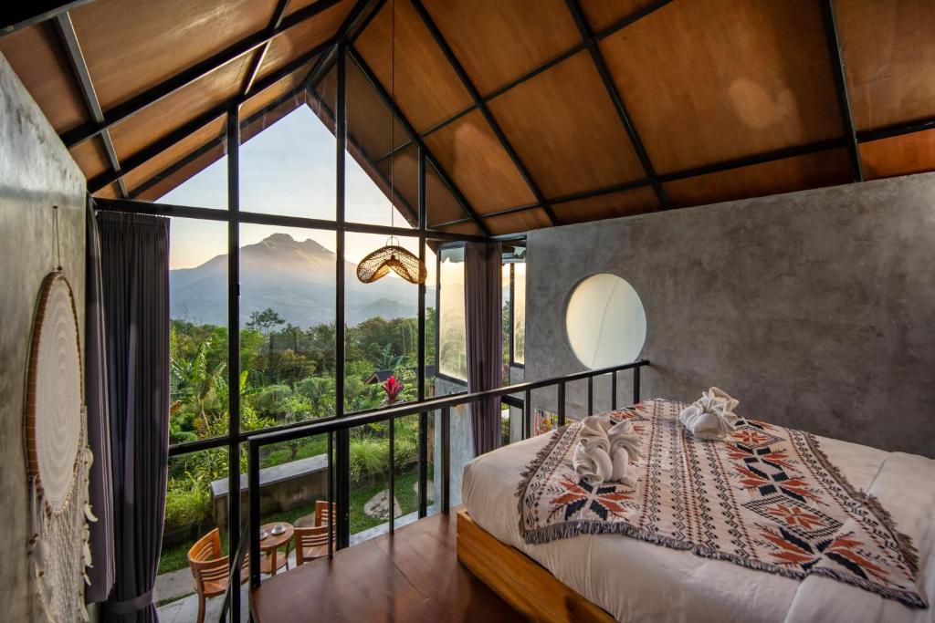sypialnia z łóżkiem i dużym oknem w obiekcie Mountain Peak Kintamani w mieście Kintamani