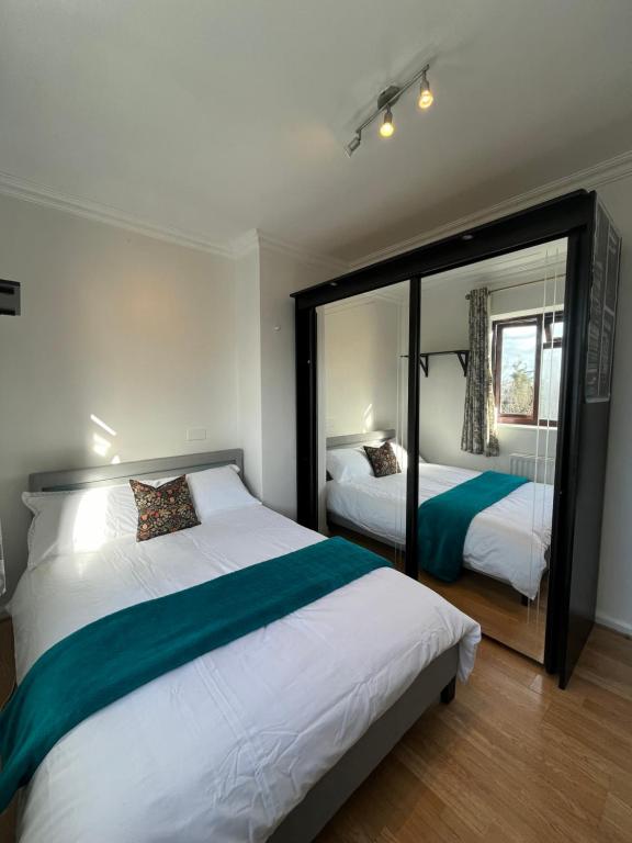 a bedroom with two beds and a large mirror at Charlton, Greenwich Service Apartment in London