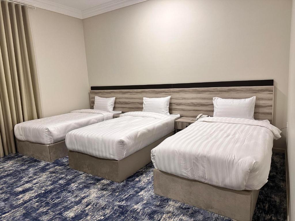 una camera d'albergo con due letti con lenzuola bianche di فندق تلاقِ a Medina