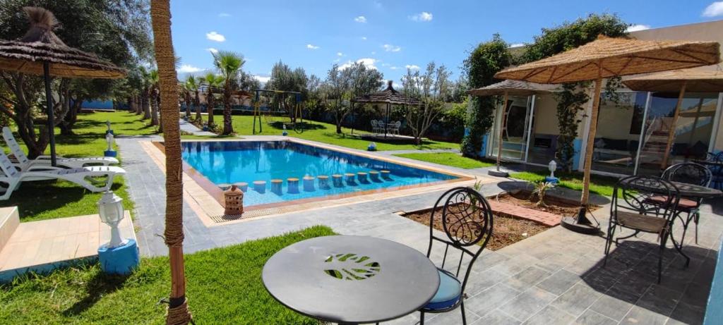 un patio trasero con piscina, mesa y sillas en Hotel Jnane riad, en Marrakech
