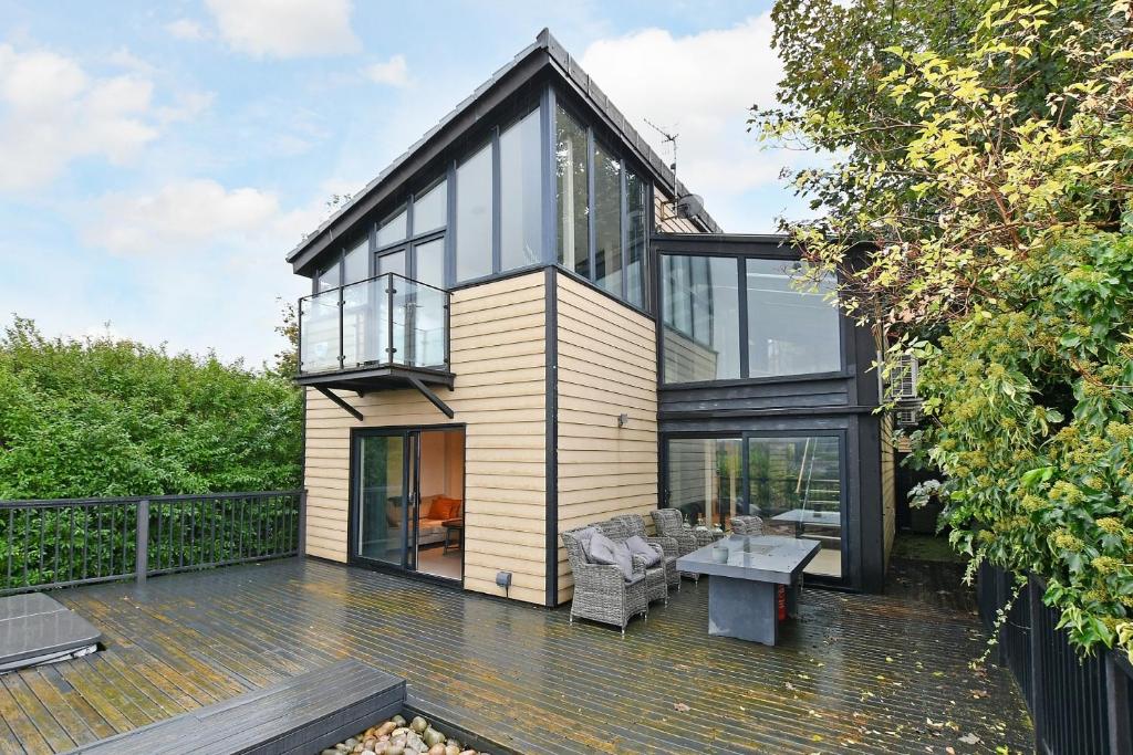 ein Haus mit Glastüren und einem Tisch auf einer Terrasse in der Unterkunft West View 3 Bedroom Villa With Hot Tub in Heeley