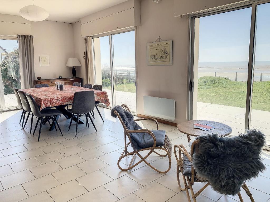 une salle à manger avec une table et des chaises et une grande fenêtre dans l'établissement Villa avec jardin et accès direct plage, terrasse, 5 chambres, 2 salles d'eau, wifi, parking - FR-1-361-132, à Saint-Pair-sur-Mer