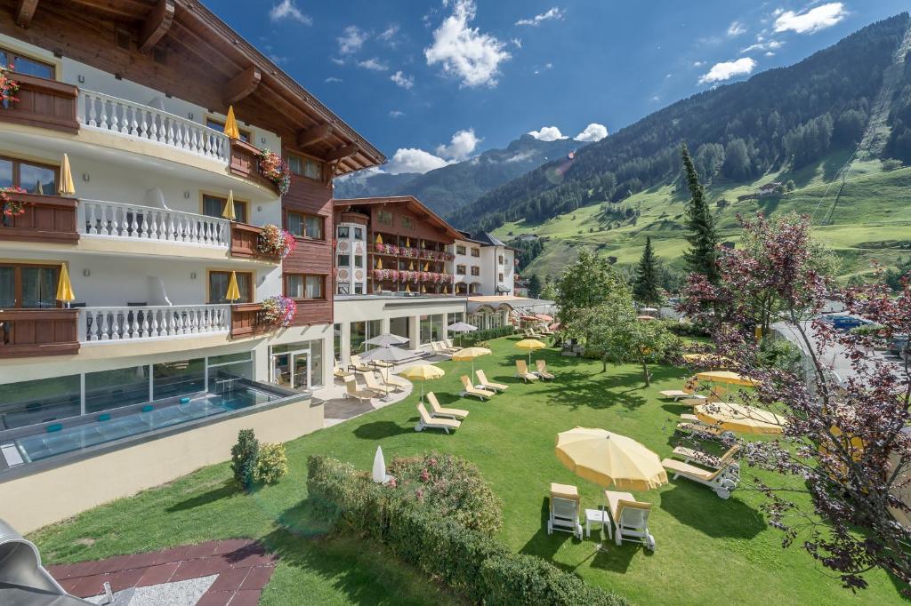a hotel with a courtyard with chairs and umbrellas at Sporthotel Neustift in Neustift im Stubaital