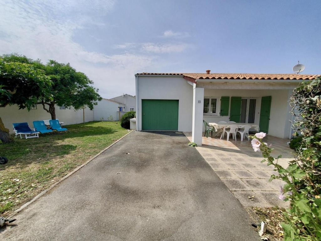 une allée menant à une maison avec un garage vert dans l'établissement Maison moderne 4 pers près du phare de Chassiron avec jardin clos, wifi, et proche plage - FR-1-778-21, à Saint-Denis-dʼOléron