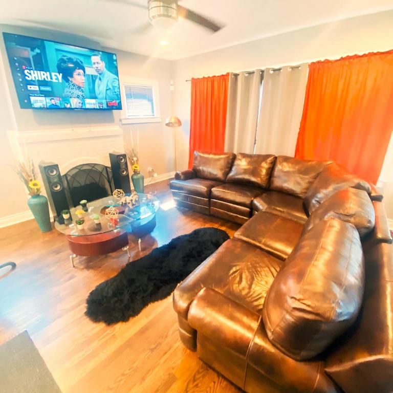 a living room with a leather couch and a tv at Fully Equipped Cozy 4/5 BR in Chicago