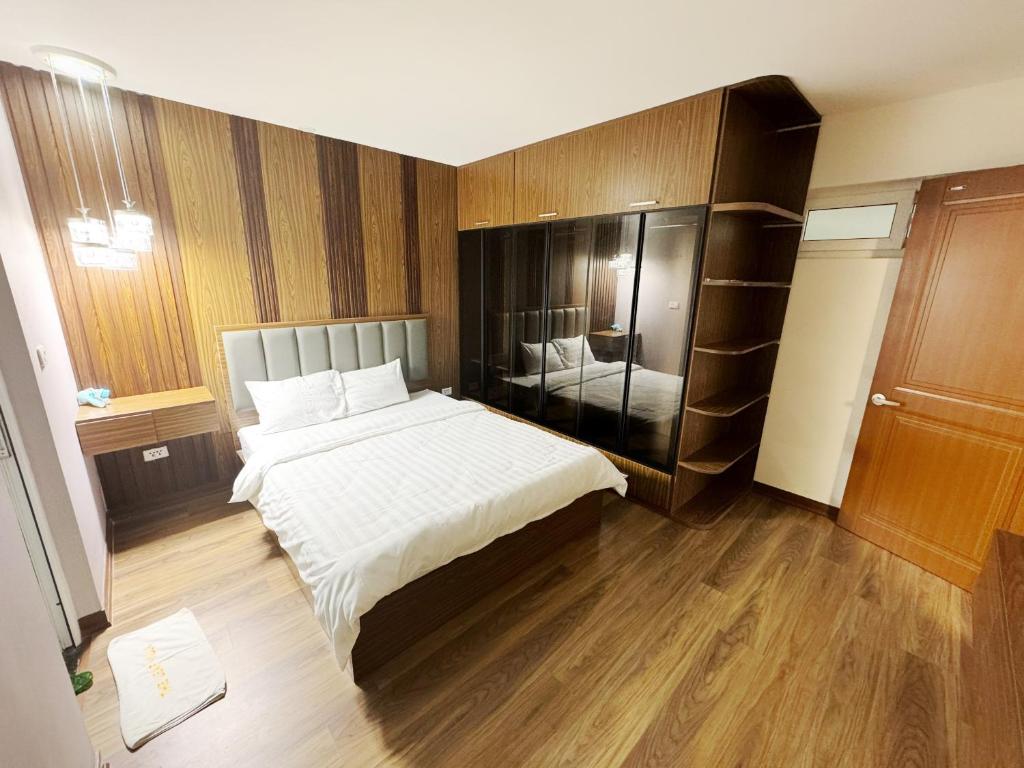 a bedroom with a large white bed and wooden floors at Ha Long Homestay in Ha Long