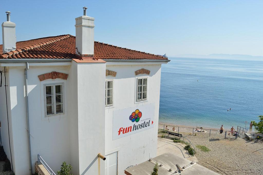 a building with a sign on it next to a beach at Hostel Fun in Rijeka