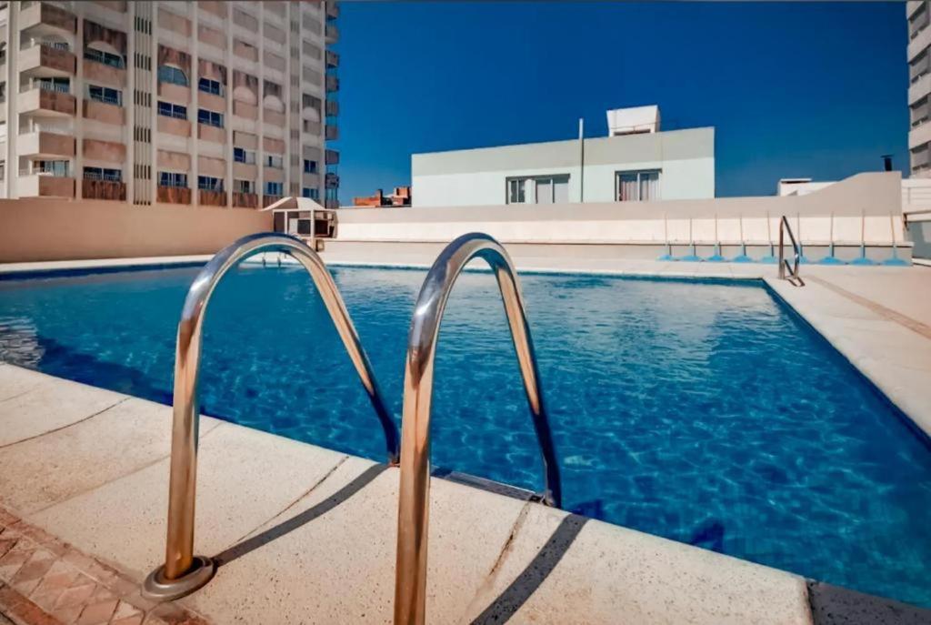 a swimming pool with a pair of metal hand rails at Apto en la península con piscina - 2 dorms - 2 baños in Punta del Este