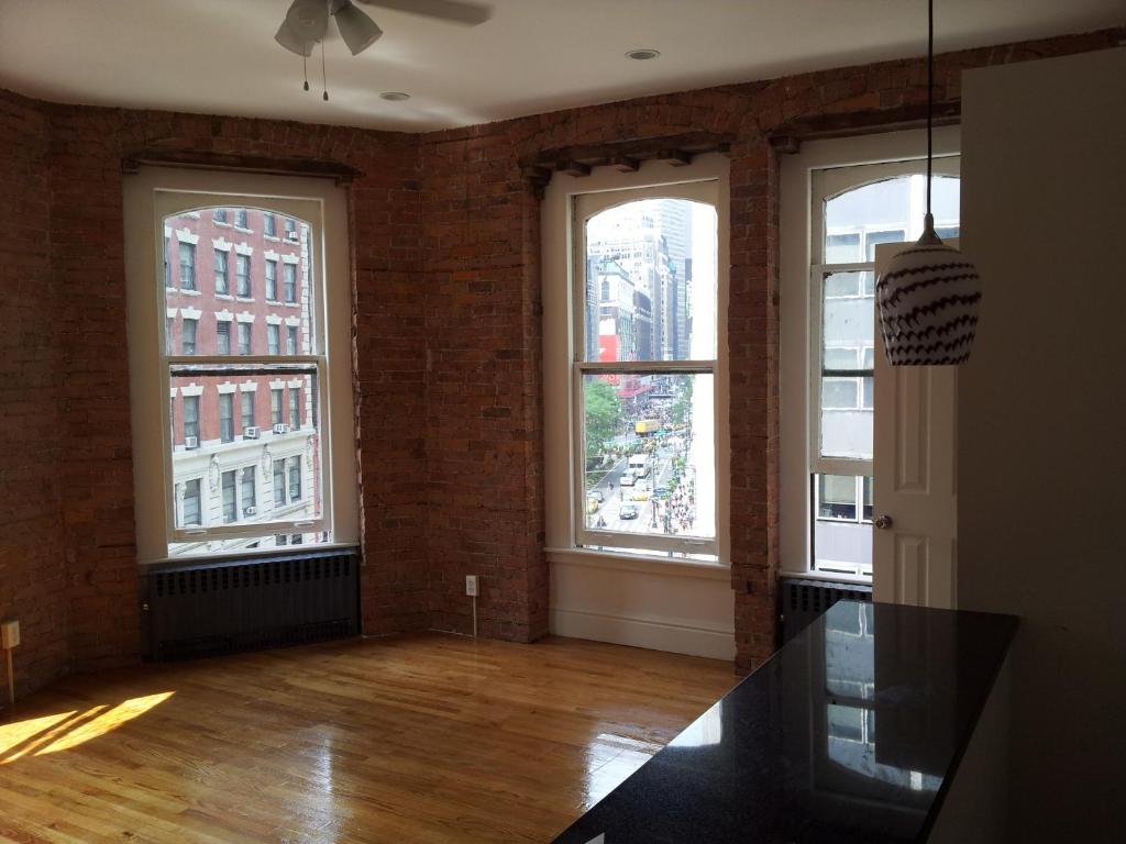 纽约Midtown Nest Loft Studio的一间空房间,楼内有三个大窗户