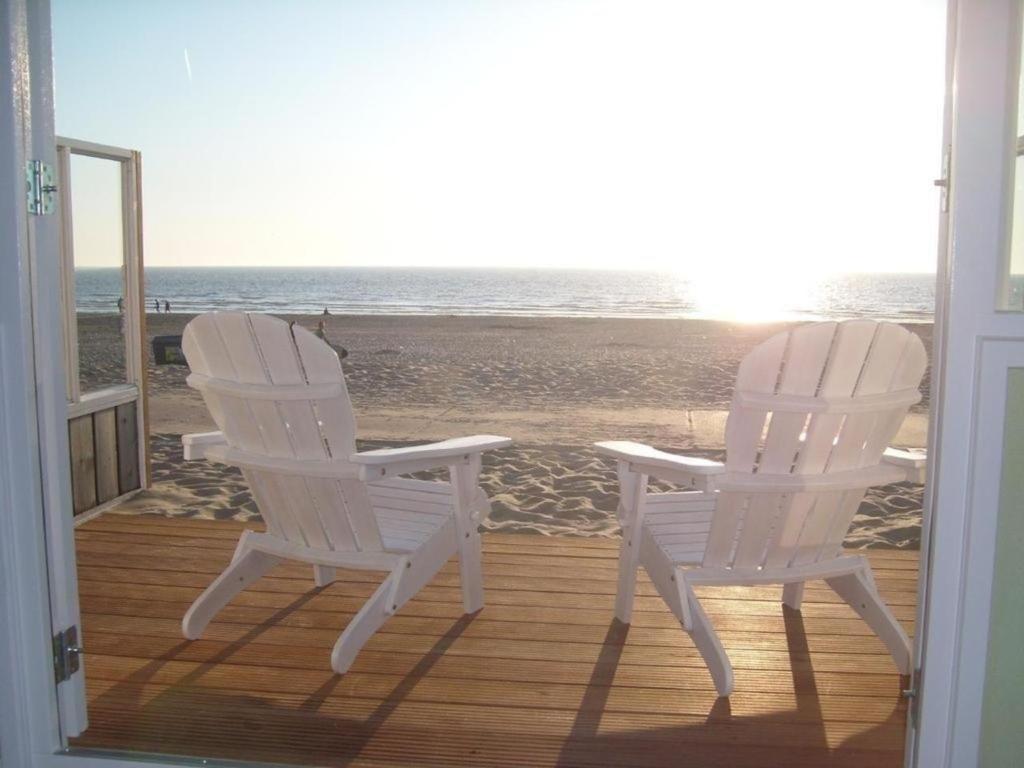 twee witte stoelen op een veranda met uitzicht op het strand bij Strandhaus direkt am Meer in Wijk aan Zee