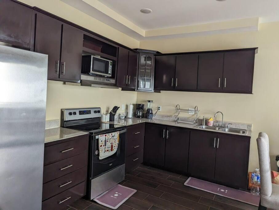 una cocina con armarios y electrodomésticos de color marrón oscuro. en Espectacular apto, acogedor para un feliz descanso, en Tegucigalpa