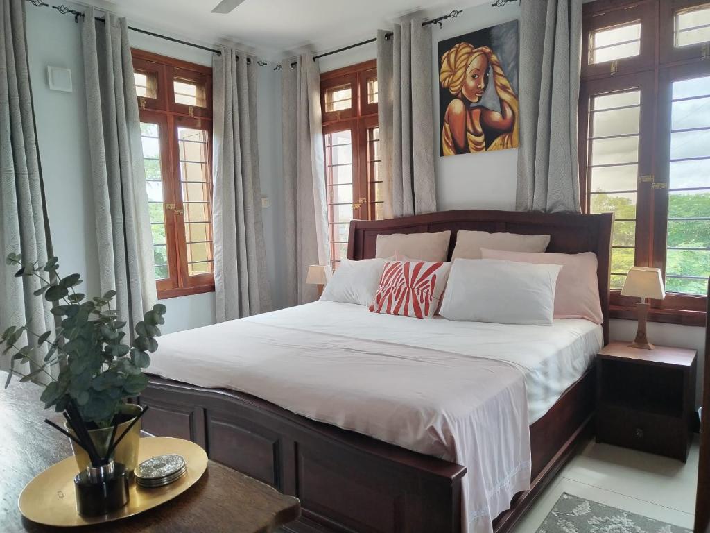 a bedroom with a bed with white sheets and windows at Funvilla Family House in Dar es Salaam
