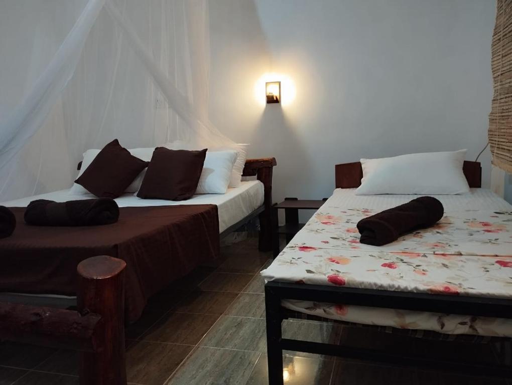 a room with two beds and a table with a bedskirts at Eco Pavilion in Sigiriya