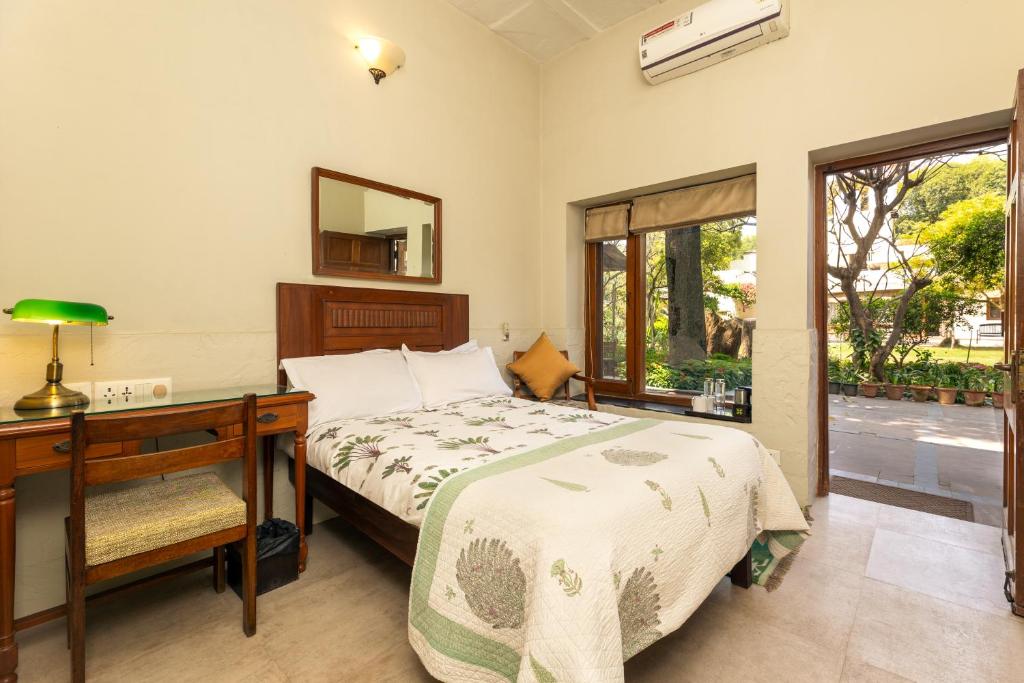 um quarto com uma cama, uma secretária e uma janela em Lutyens Bungalow em Nova Deli