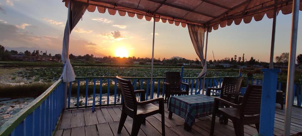a table and chairs on a deck with the sunset at Houseboat wild rose in Srinagar