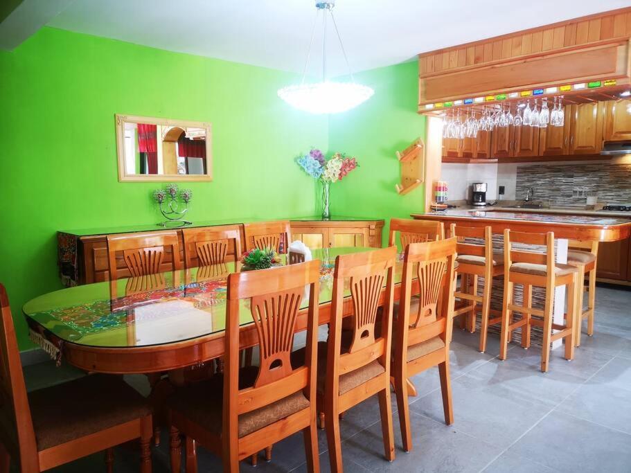 ein Esszimmer mit grünen Wänden sowie einem Tisch und Stühlen in der Unterkunft Casa Judá in San Cristóbal de las Casas