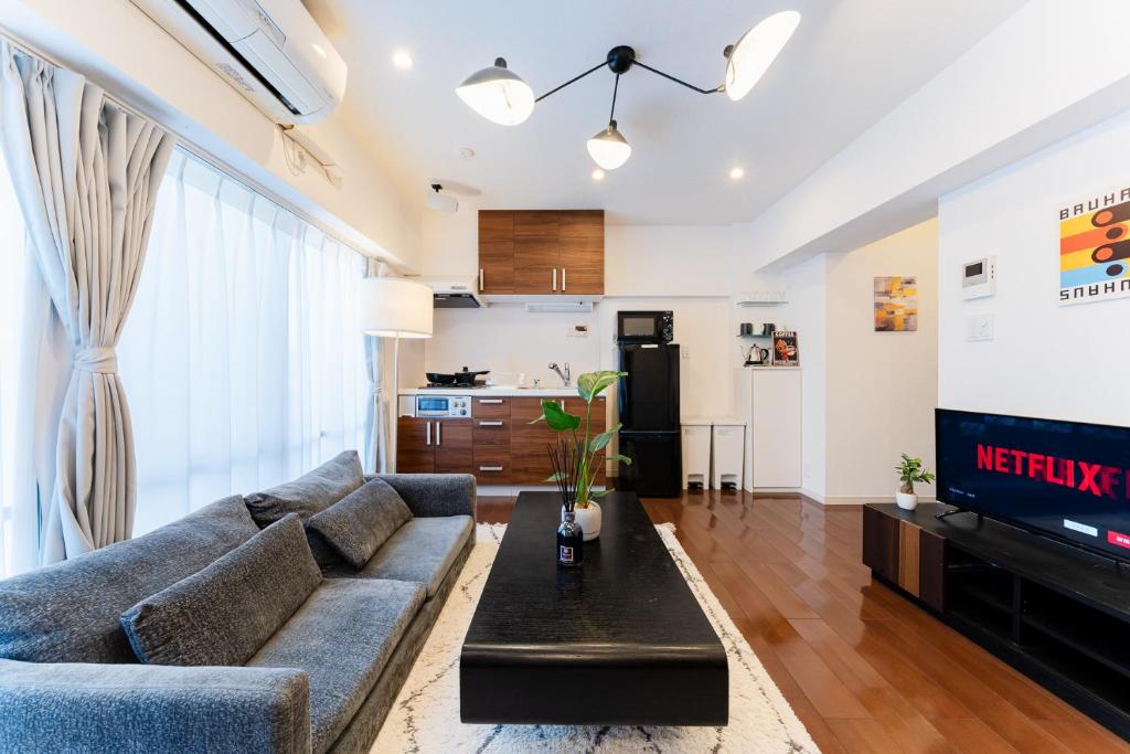 a living room with a couch and a tv at SAKURA Residence目黒駅前 Standard in Tokyo