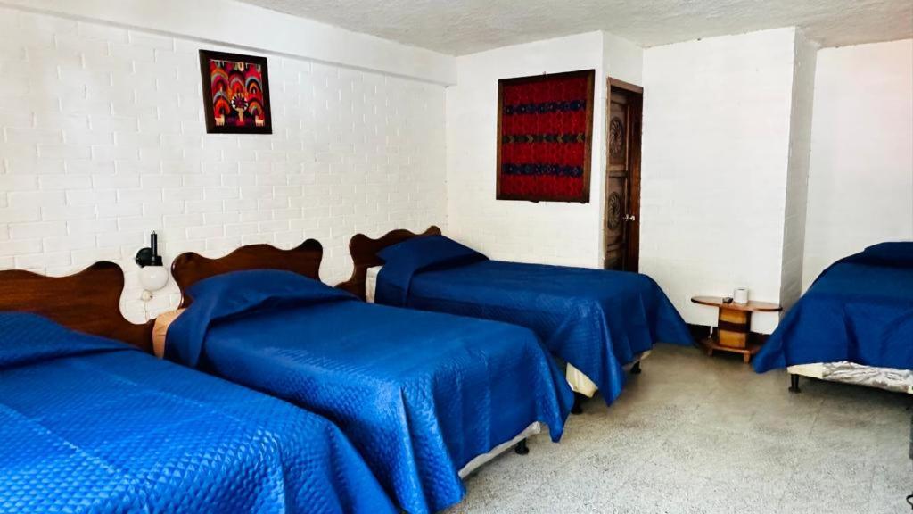 1 Schlafzimmer mit 3 Betten und blauer Bettwäsche in der Unterkunft Royal Palace Hostal in Panajachel