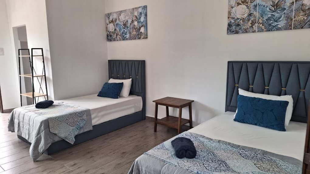 una camera con 2 letti con cuscini blu di Ocean Cottage 3, Radiant Teluk Sari a Kampung Mawar