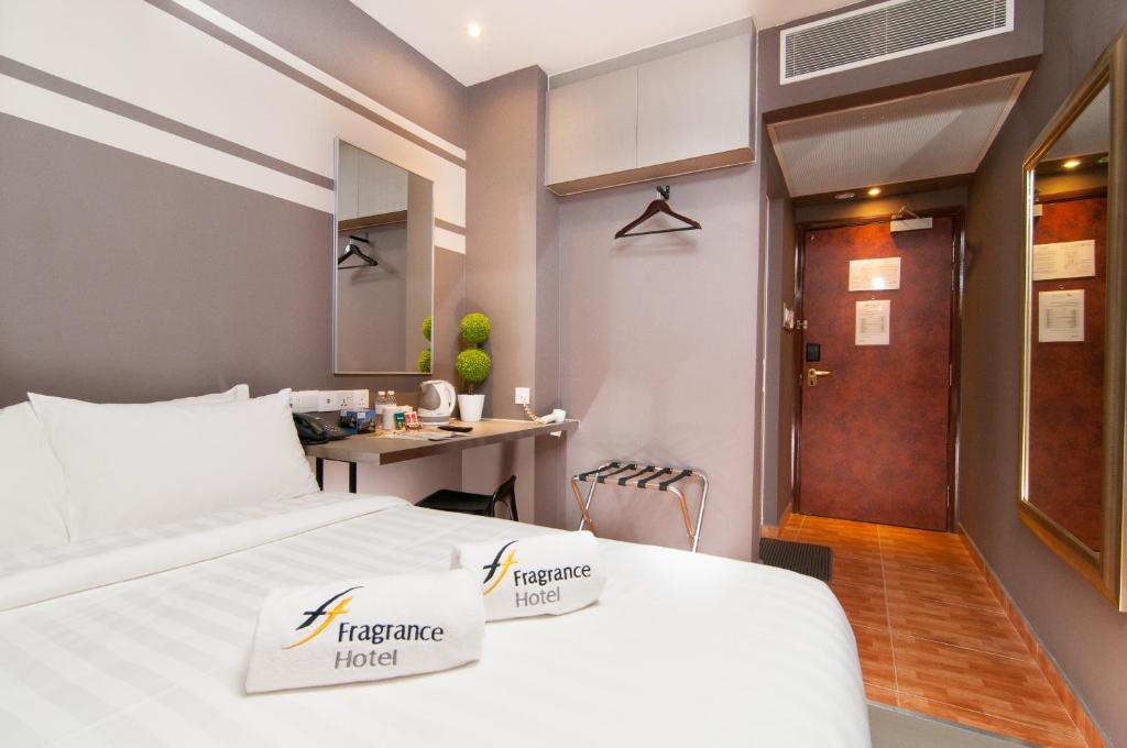 a hotel room with a bed and a desk at Fragrance Hotel - Kovan in Singapore