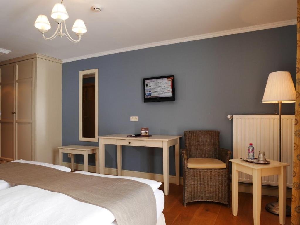a hotel room with two beds and a table and a chair at Hotel Eifelland in Butgenbach