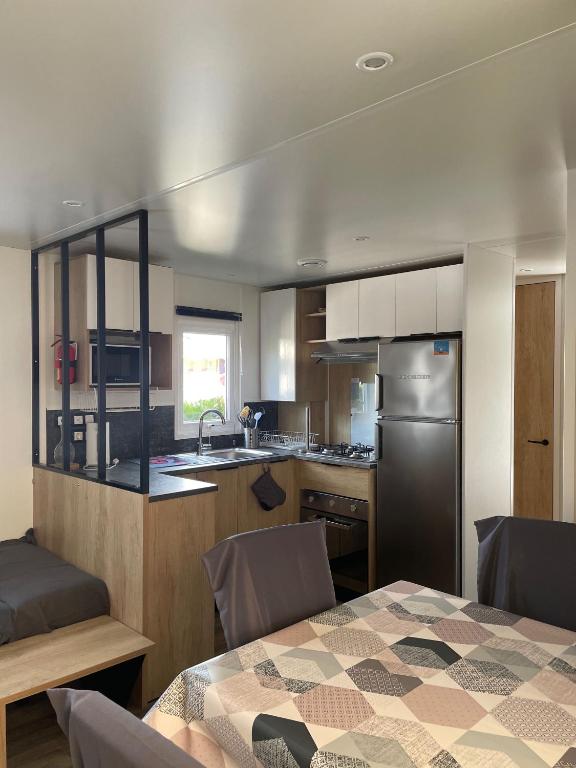 Il comprend une cuisine équipée d'une table et d'un réfrigérateur. dans l'établissement Mobilhome Ck135 Siblu Les Charmettes, aux Mathes