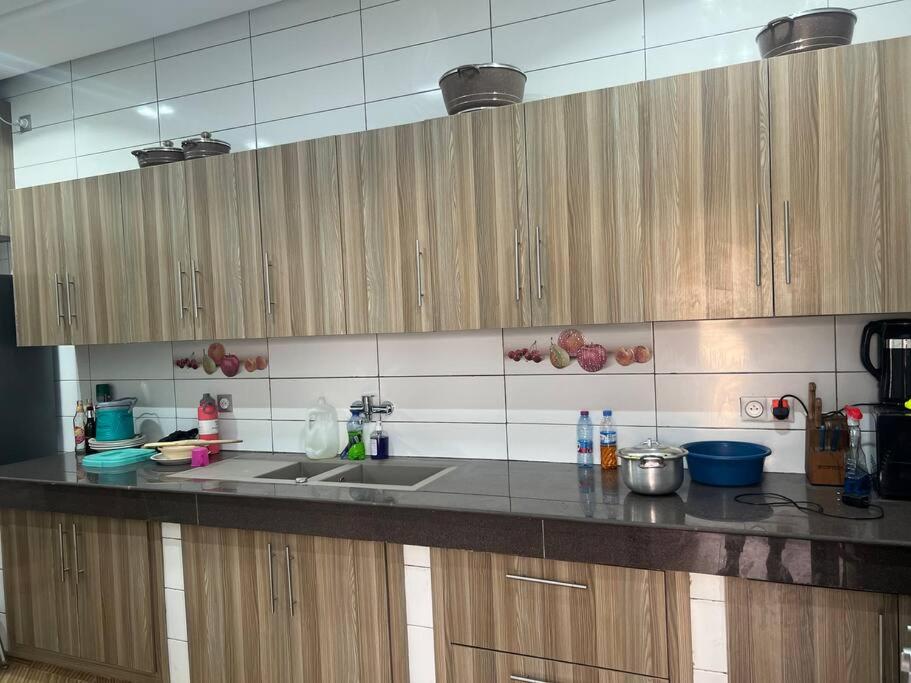 a kitchen counter with a sink and wooden cabinets at Brand New Luxurious Villa in Lomé Bê kpota in Lomé