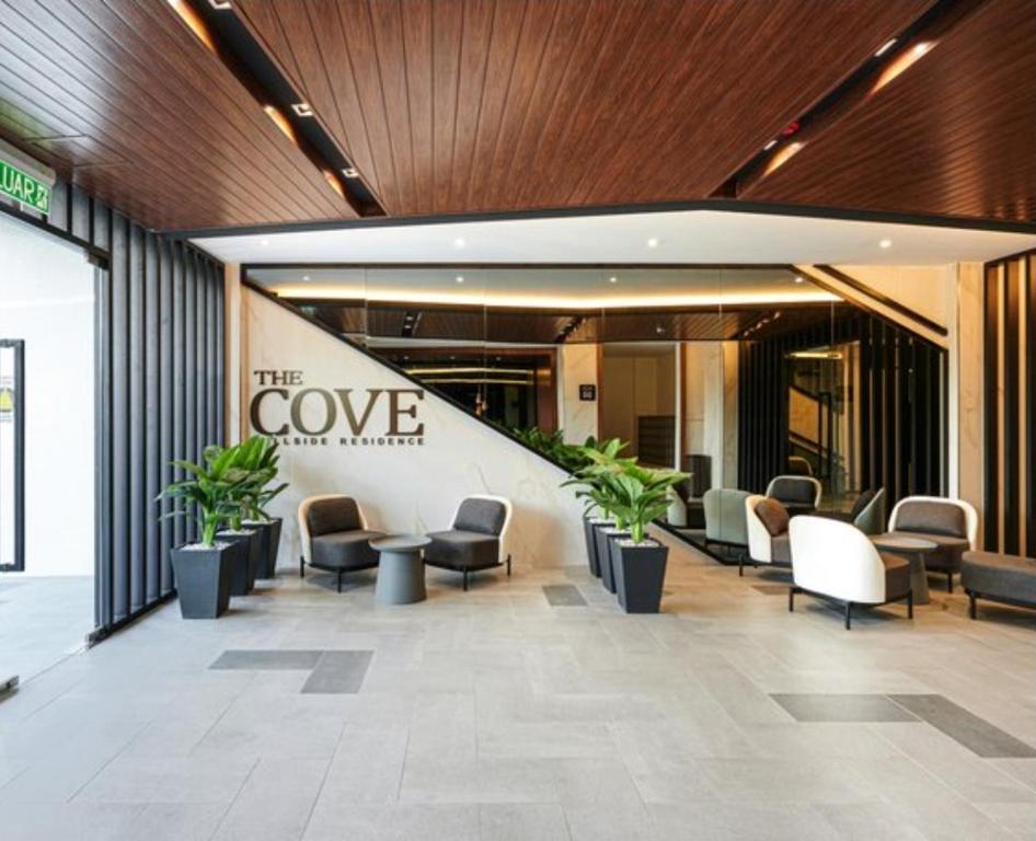 イポーにあるThe Cove Hillside Condominiumの建物内の椅子と植物が置かれたロビー