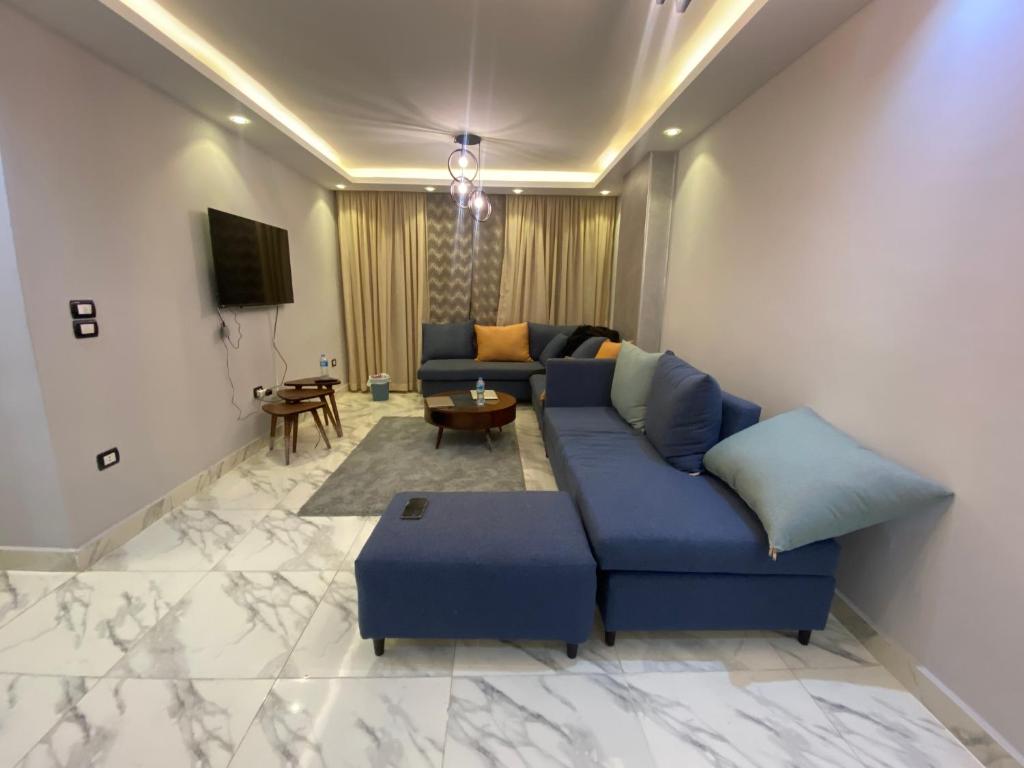 uma sala de estar com um sofá azul e uma televisão em Holiday In Downtown no Cairo