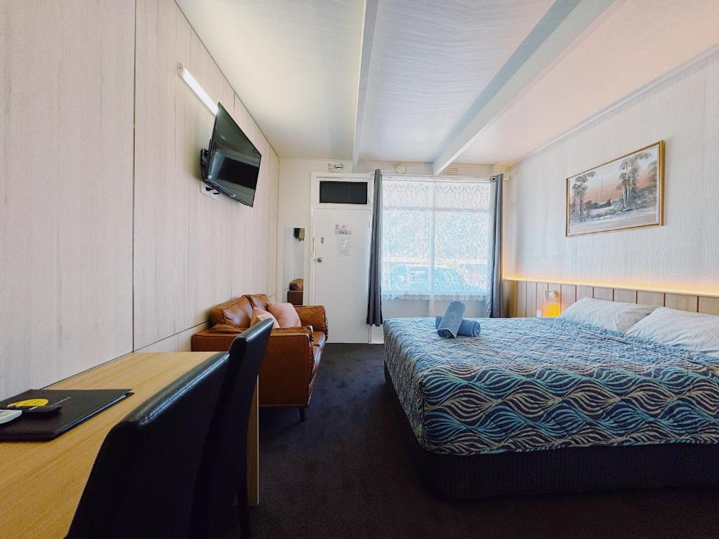 a hotel room with a bed and a chair and a desk at Seymour Motel in Seymour