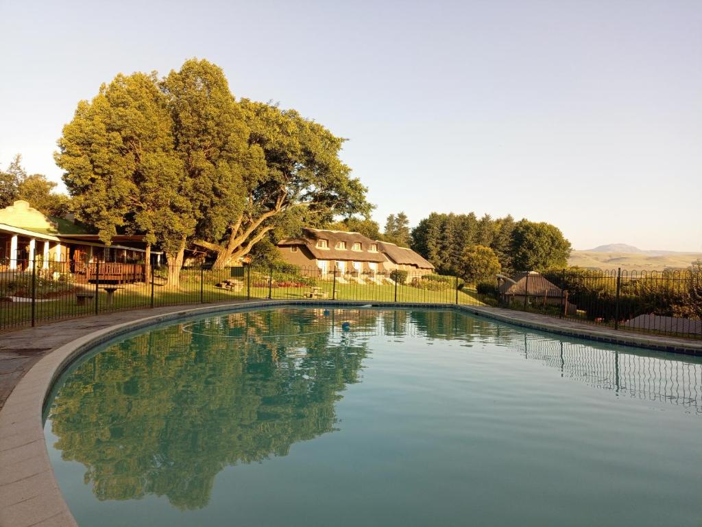 uma grande piscina com uma cerca em redor em The Nest Drakensberg Mountain Resort Hotel em Champagne Valley