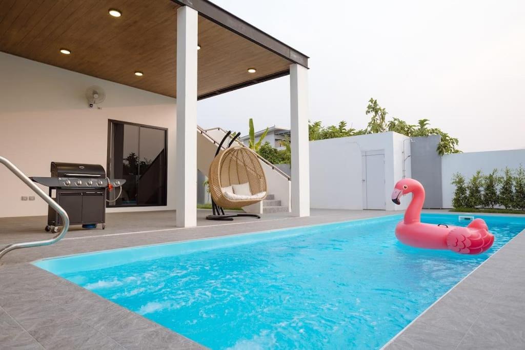 un flamingo rose dans une piscine dans une maison dans l'établissement 清迈现代豪华泳池独栋别墅 可配埃尔法包车专属司机 （Chang king villa）, à Ban Khun Se