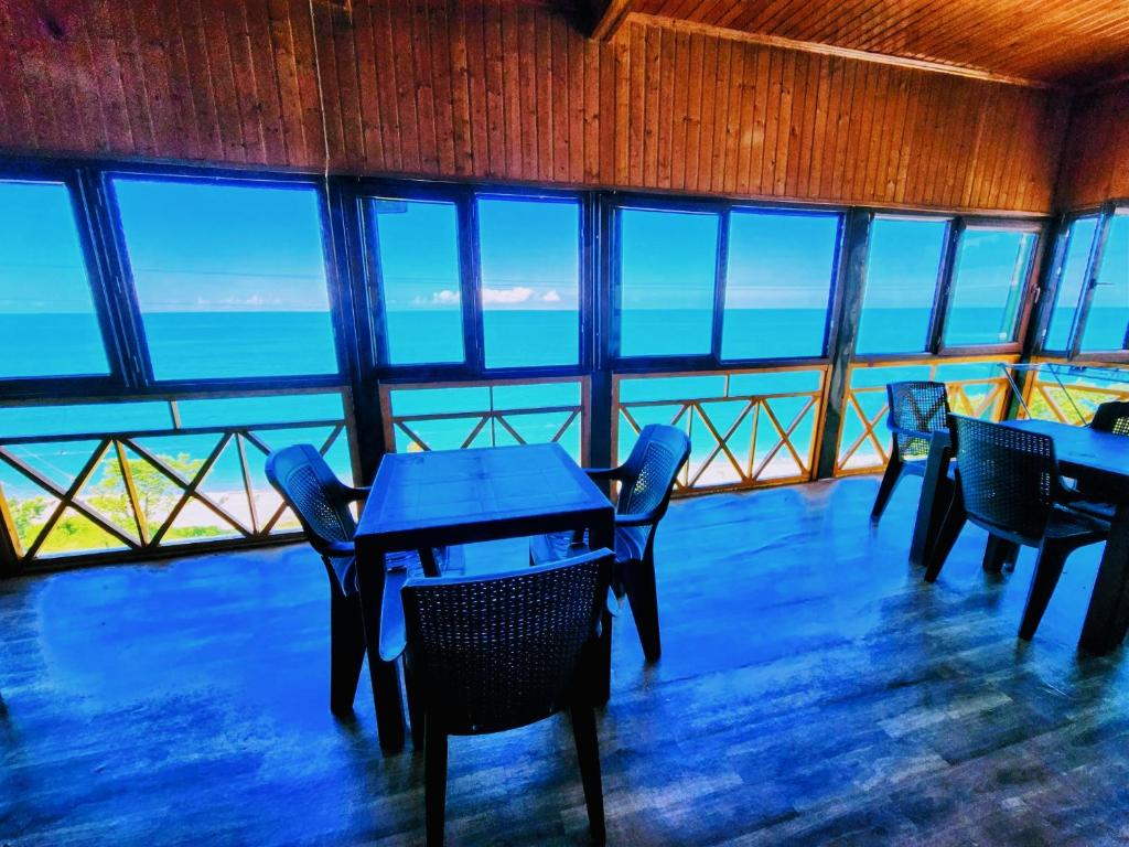 a dining room with tables and chairs and the ocean at GUEST HOUSE NONA in Chakvi