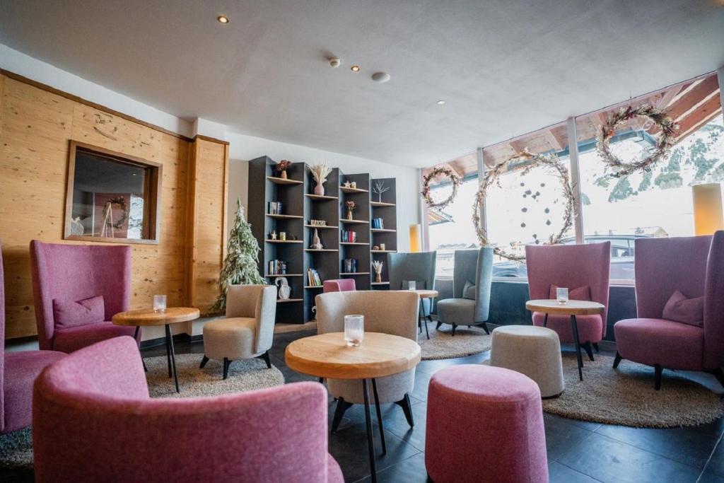 a restaurant with pink chairs and tables and shelves at Hotel Alpenrose aktiv & sport in Kühtai