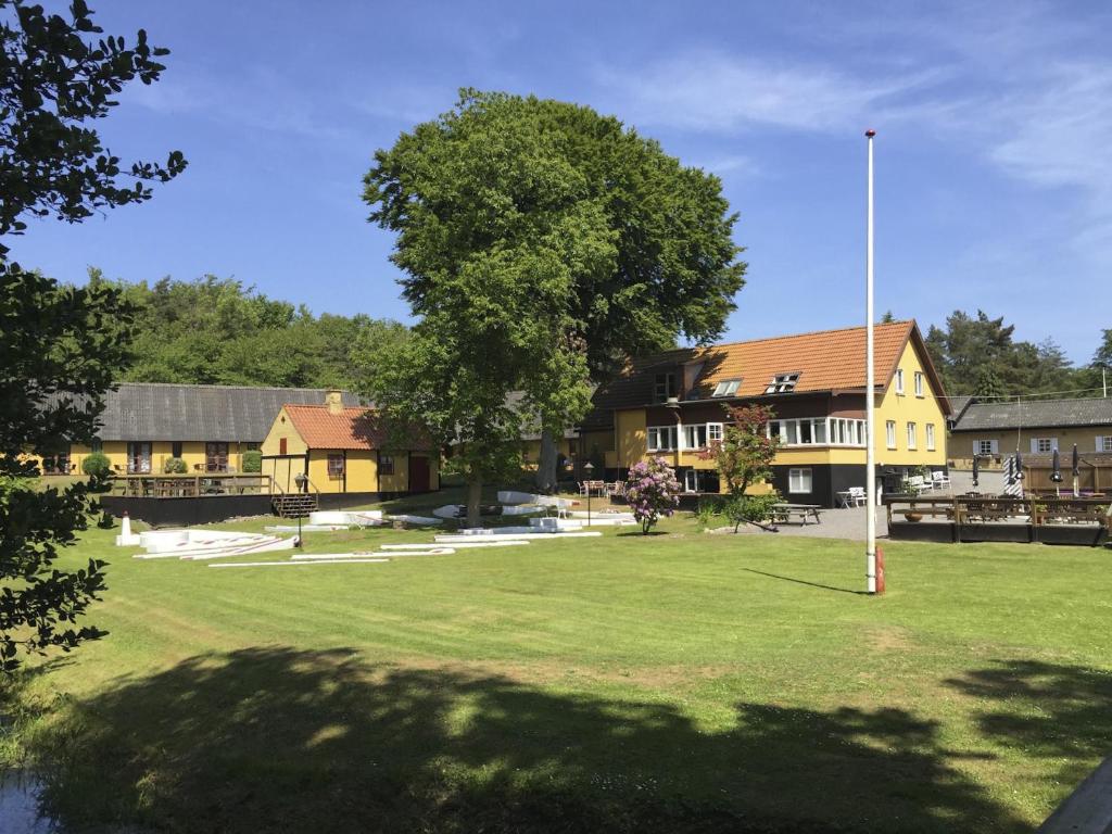 ein Gebäude mit einem Baum in der Mitte eines Feldes in der Unterkunft Hotel Skovly in Rønne