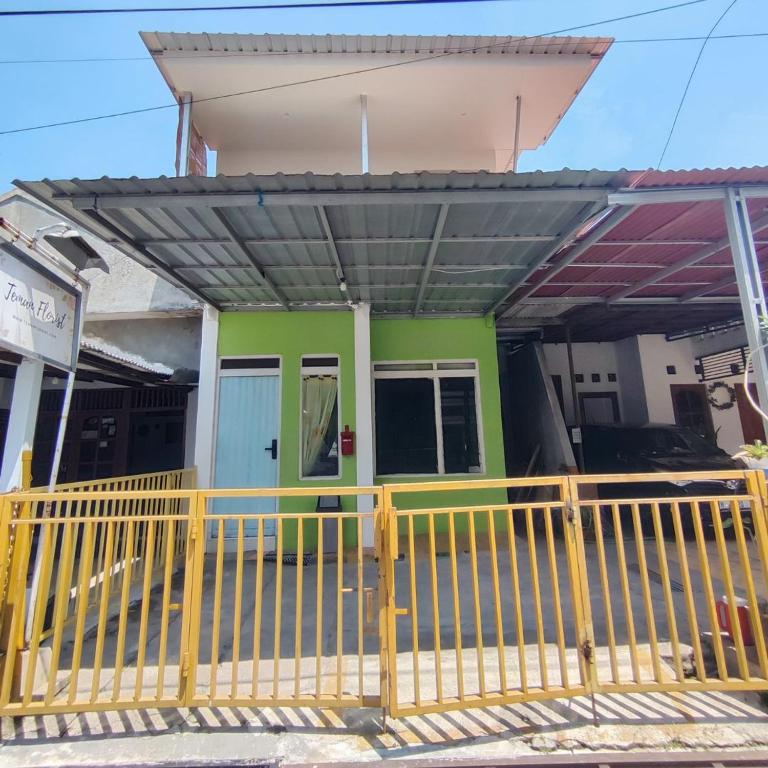 uma casa com uma cerca amarela à frente. em Rumah Teman Homestay em Semarang