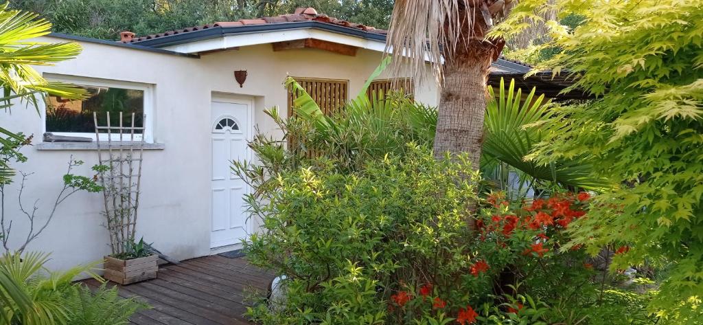 uma pequena casa branca com um deque de madeira em Studio avec jardin à 2km de L'Océan ! em Labenne