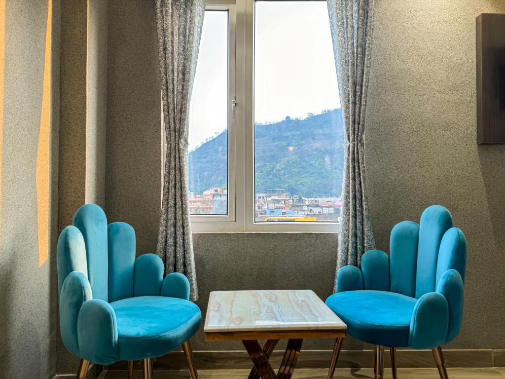 zwei blaue Stühle und ein Tisch vor einem Fenster in der Unterkunft Hotel The Mantra , Haridwar in Haridwar
