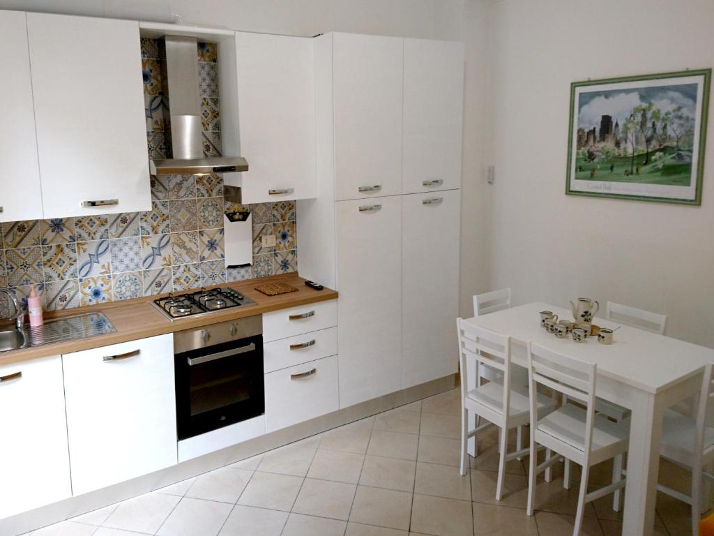 uma cozinha com armários brancos e uma mesa com cadeiras em Grottammare mon amour Lori, con cortile privato em Grottammare