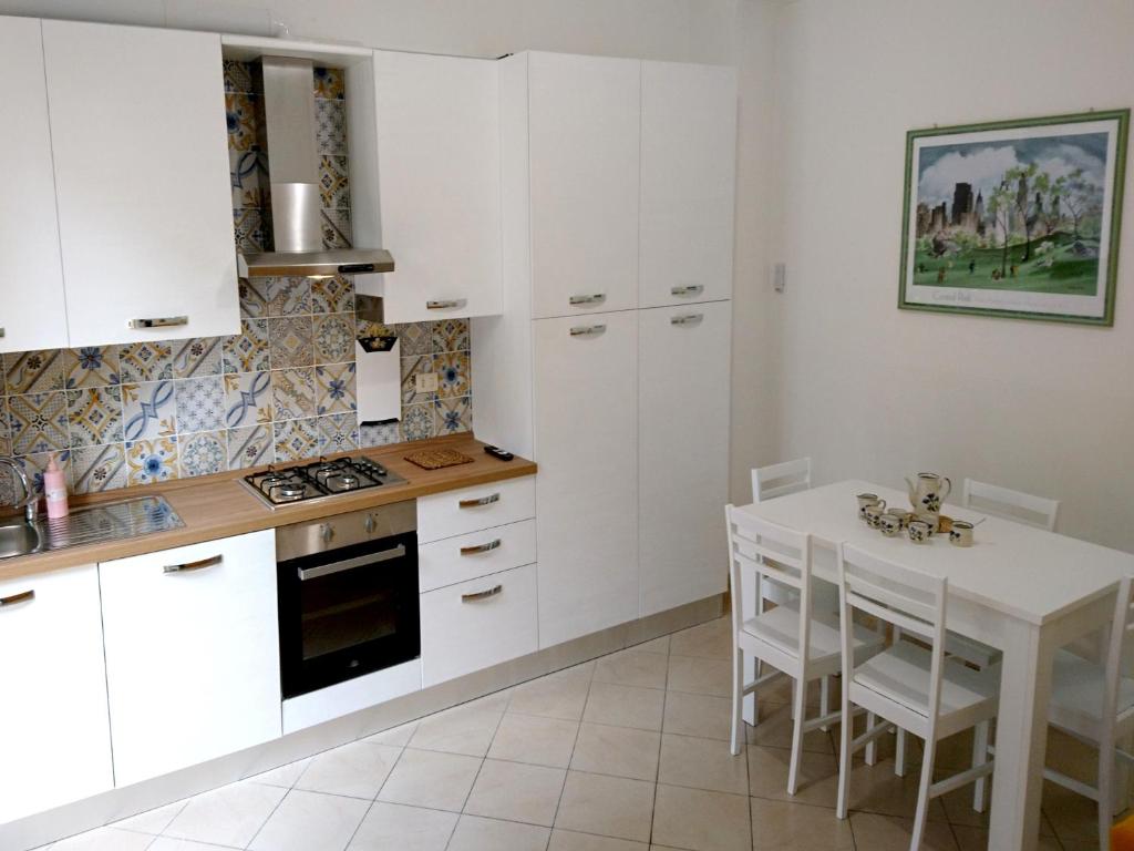 a kitchen with white cabinets and a table with chairs at Grottammare mon amour Lori, con cortile privato in Grottammare