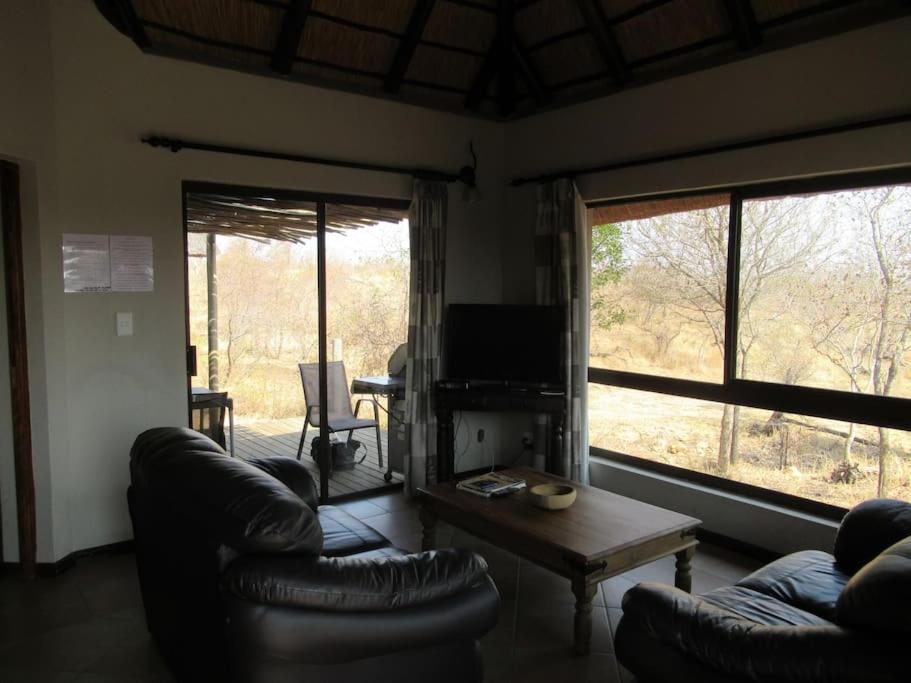 een woonkamer met banken en een tafel en een televisie bij Elephants' Cottage - 102 Mjejane Game Reserve, KNP in Hectorspruit